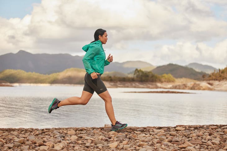 A woman running beside a river.